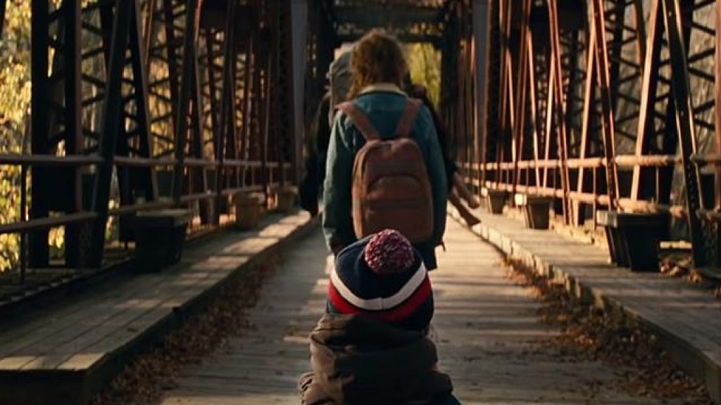A group walks in single file over a bridge, away from the camera