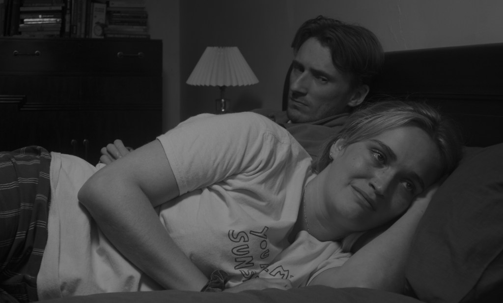 a man and a woman in bed, looking displeased.