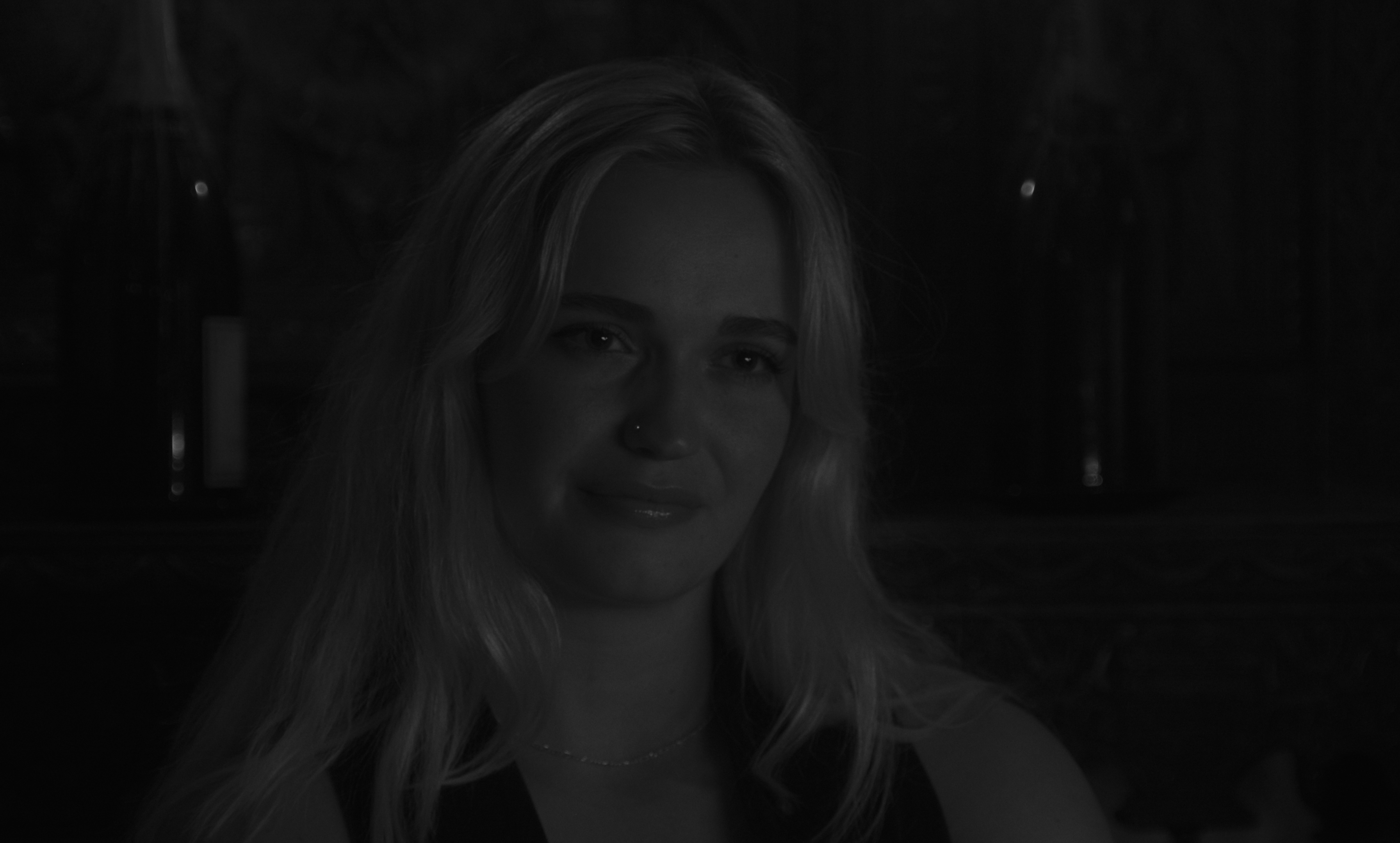 a woman up close, smiling with sadness in her eyes,